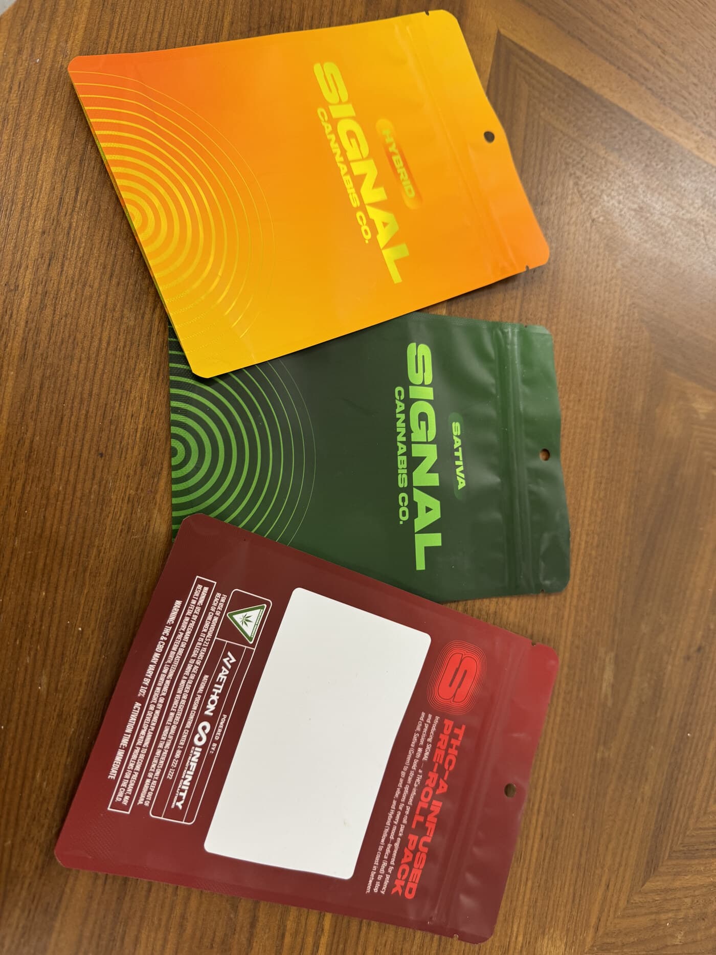A partner brand's retail mylar — Hybrid, Sativa, and a THCA-infused pre-roll pack with a fully compliant back panel. Co-packed and finished in-house under their own artwork.